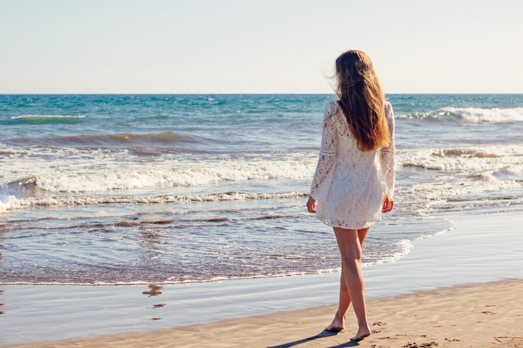 kobieta w białej sukience na plaży